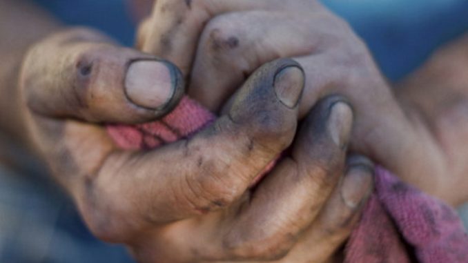 Closeup of a man's dirtied, bloodied hands.